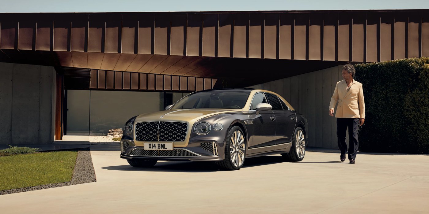 Bentley San Juan Bentley New Flying Spur Mulliner V8 hybrid sedan front three quarters in Rose Gold over Magnetic paint, parked near modern home