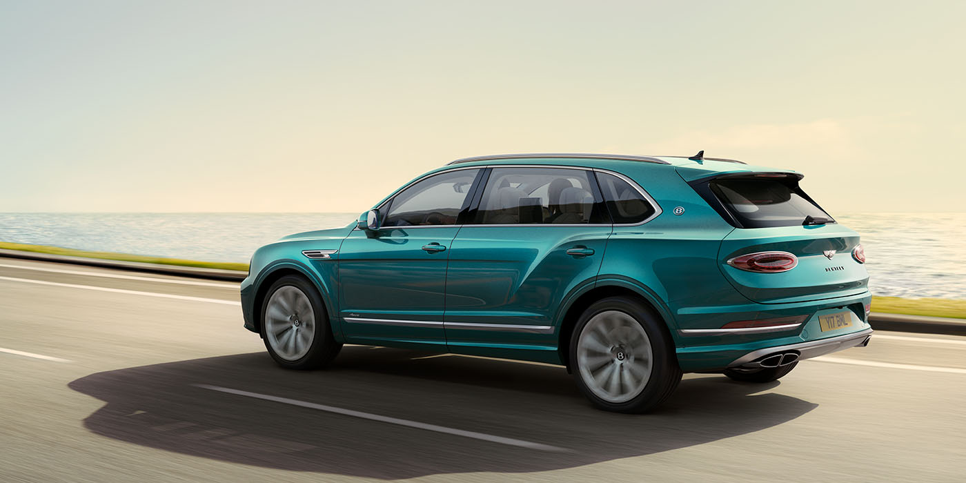 Bentley San Juan Bentley Bentayga Extended Wheelbase Azure luxury SUV rear three quarter in Topaz Blue by Mulliner paint, driving on an ocean road.