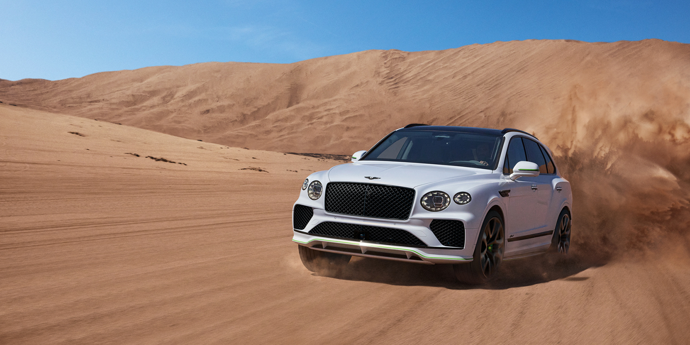 Bentley San Juan Bentley Bentayga Speed SUV front three quarter in Snow Quarts Pearlescent by Mulliner white paint driving dynamically through the desert