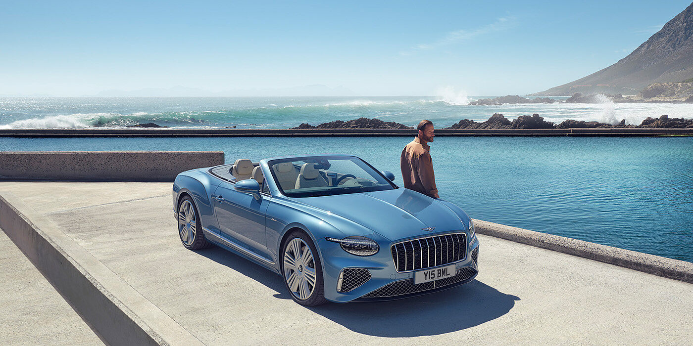 Bentley San Juan New Bentley Continental GTC Azure convertible front view in Light Windsor blue paint with 22 inch ten spoke wheels parked by the sea in the sunshine