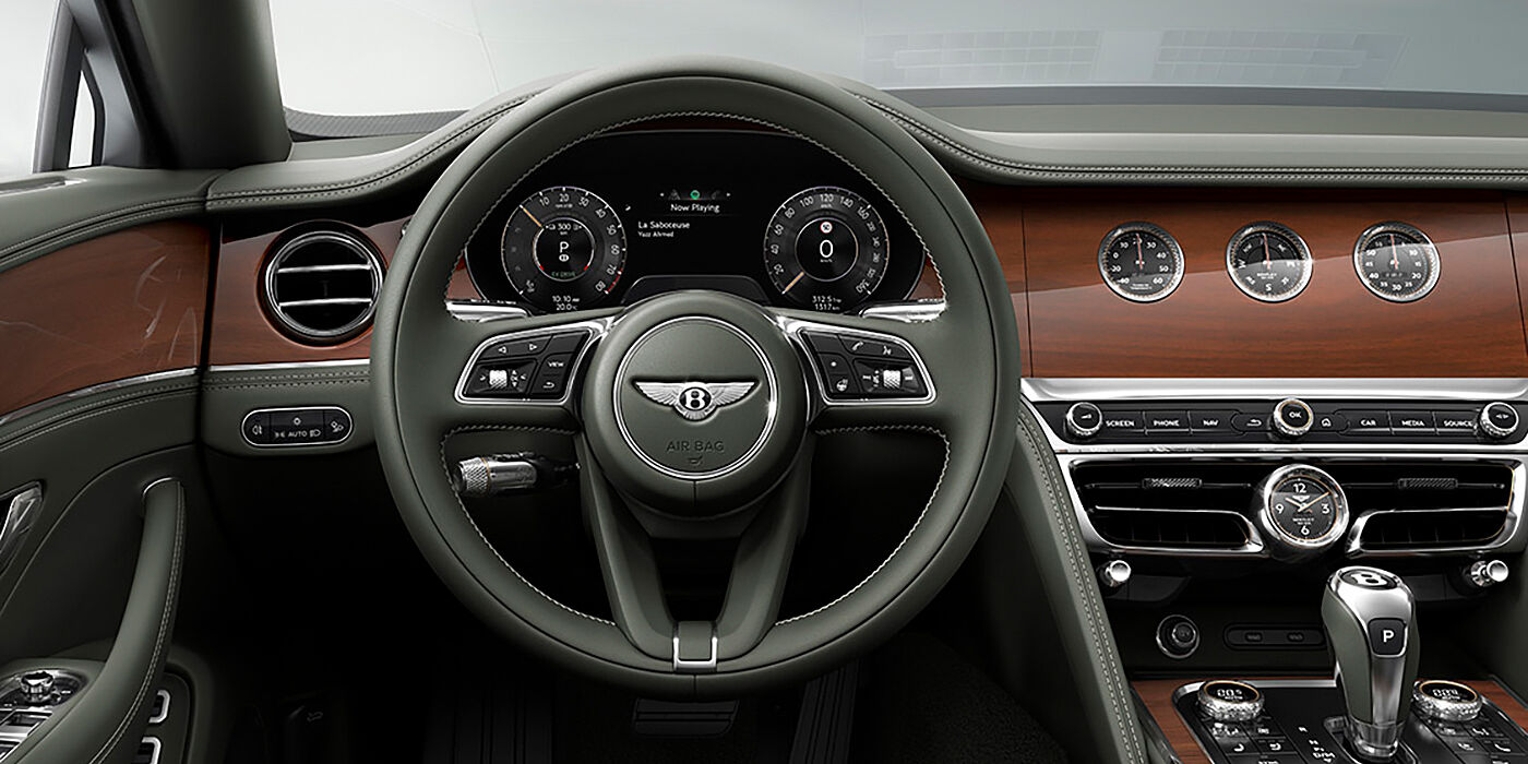 Bentley San Juan New Bentley Flying Spur sedan front cabin in Cumbrian Green hide and Crown Cut walnut veneer showing steering wheel and Rotating Display with three clocks on face