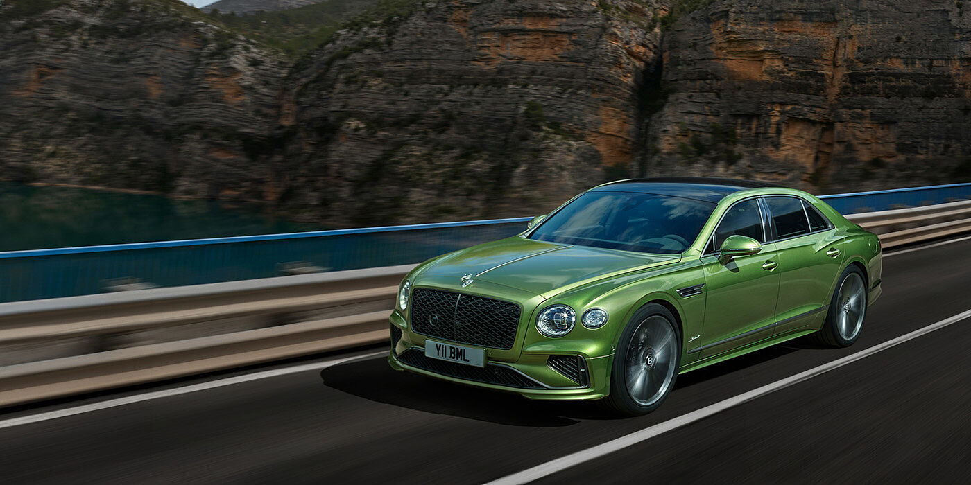 Bentley San Juan Bentley New Flying Spur Speed v8 hybrid sedan driving dynamically on a mountain road in Tourmaline Green paint