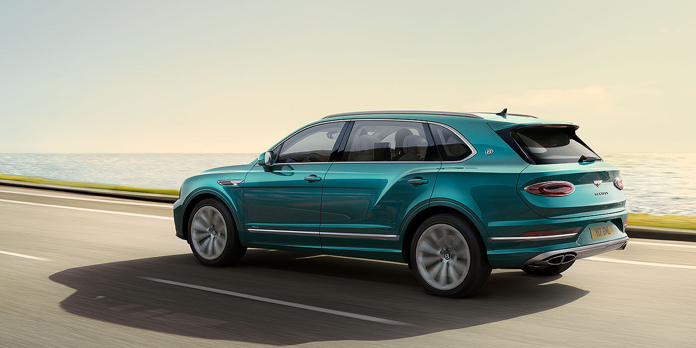 Bentley San Juan Bentley Bentayga Extended Wheelbase Azure luxury SUV rear three quarter in Topaz Blue by Mulliner paint, driving on an ocean road.