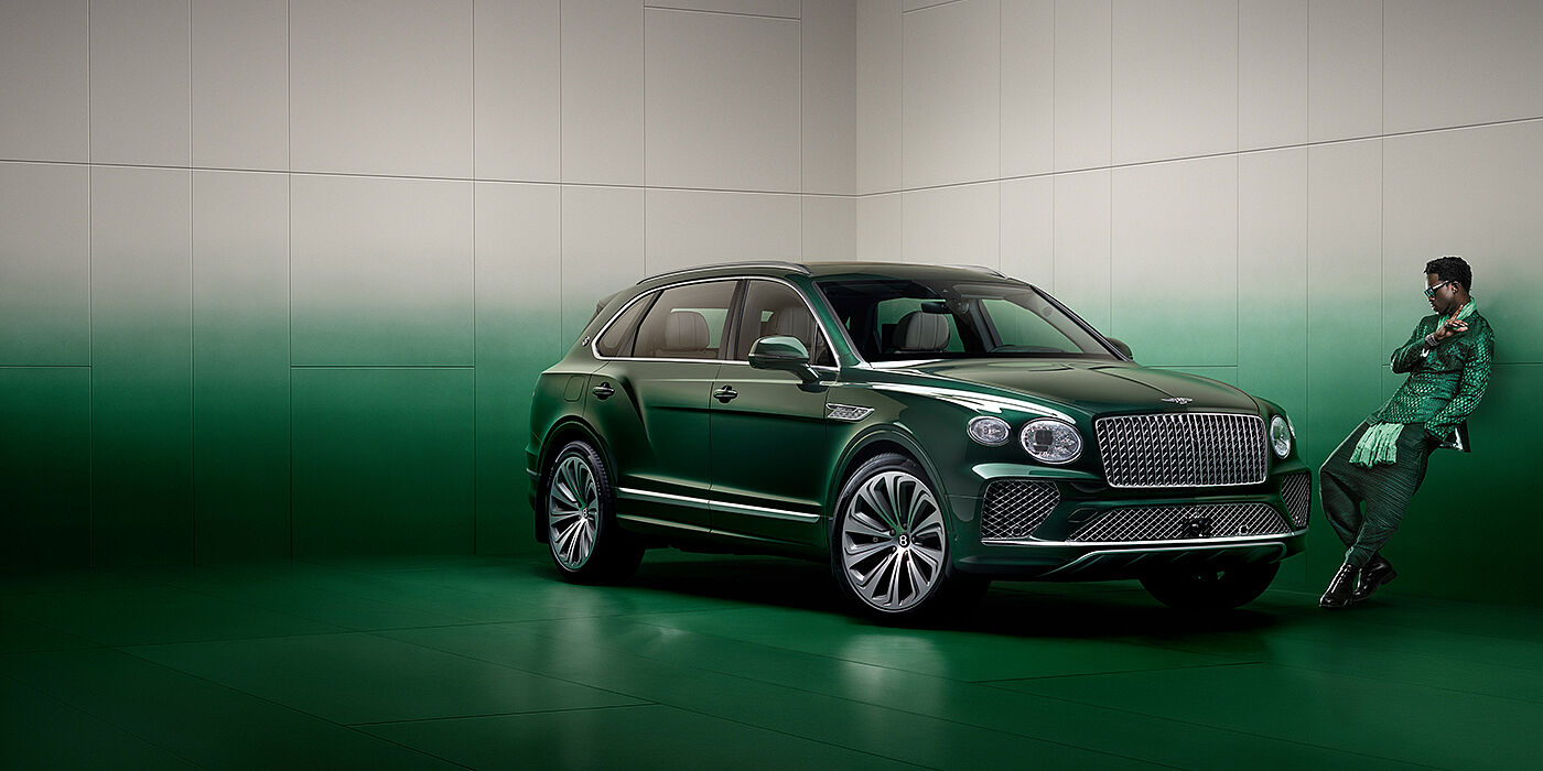 Bentley San Juan Wisdom K leans against wall next to Bentley Bentayga Extended Wheelbase Atelier Edition SUV in Light Emerald green paint
